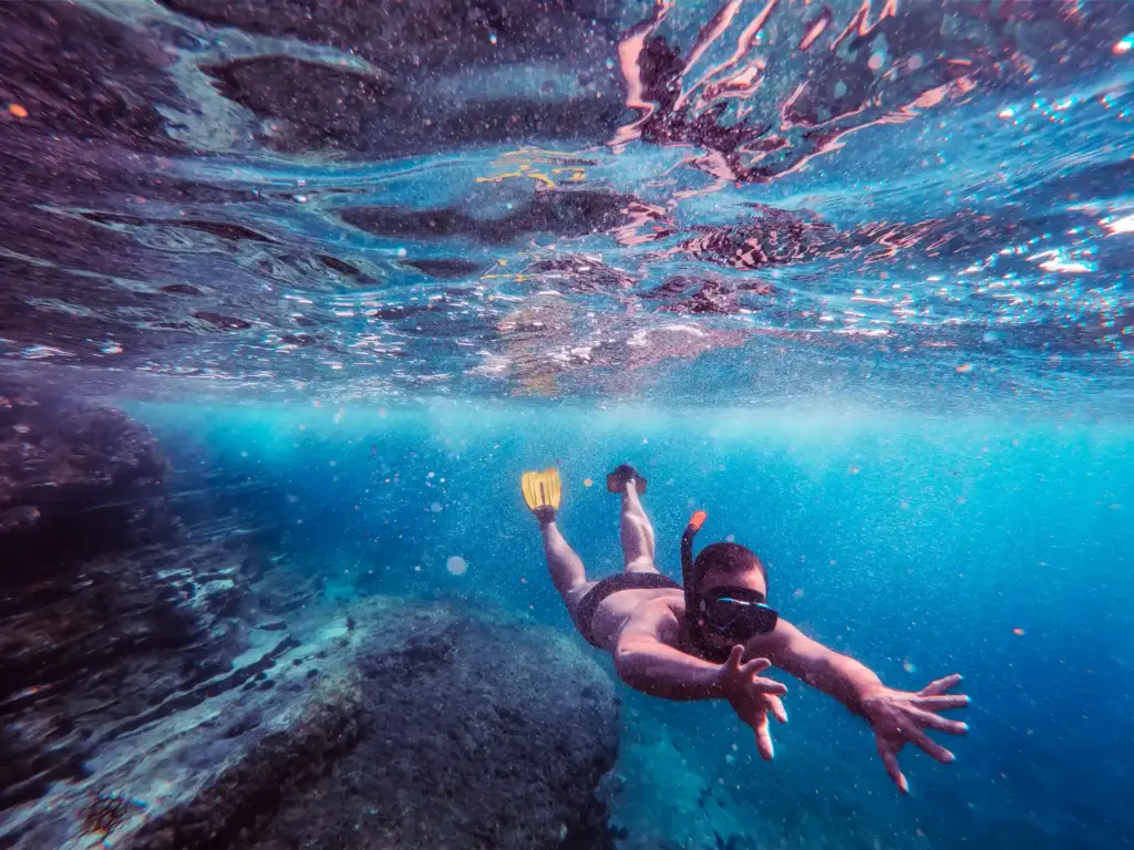Man snorkeling with mask and yellow fins in Malta’s clear water