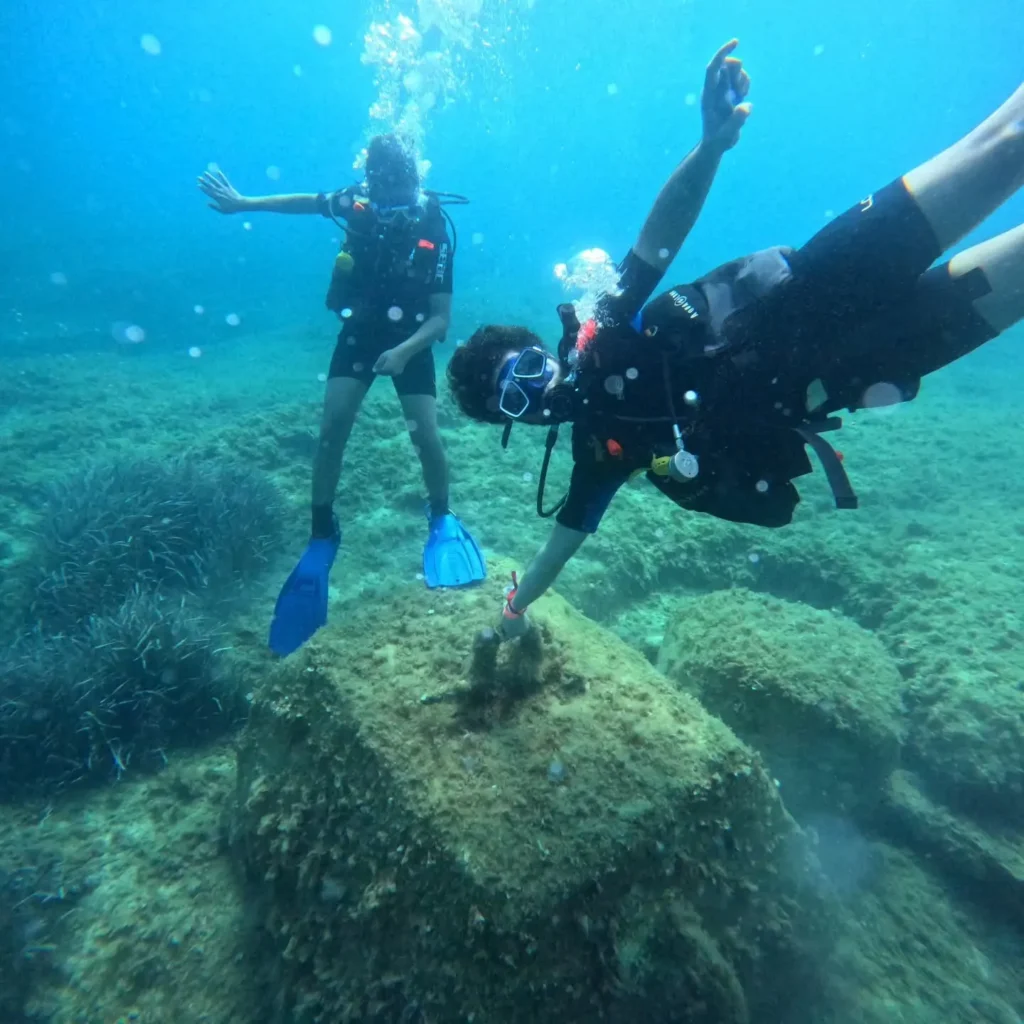Two divers enjoying their first dive over Malta’s rocky seabed