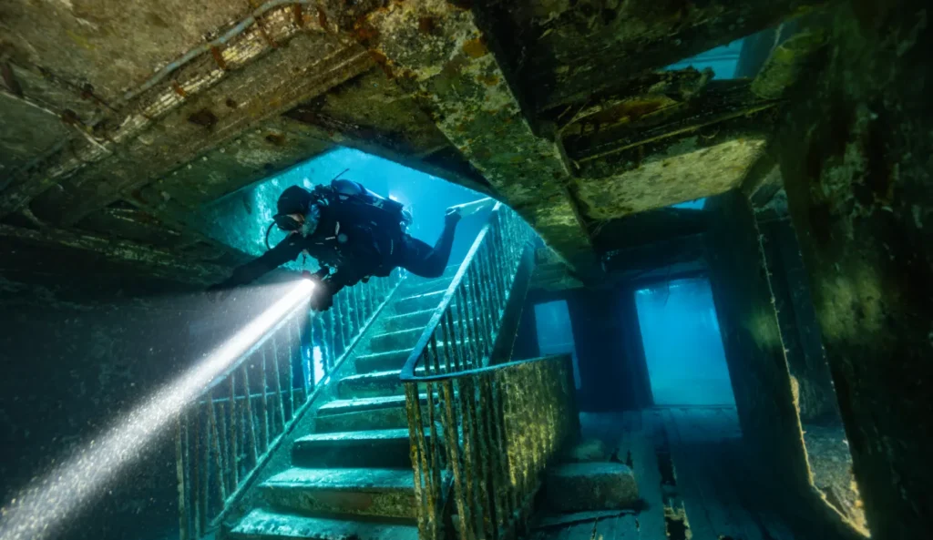 Diver lighting the staircase inside the MV Karwela wreck in Gozo