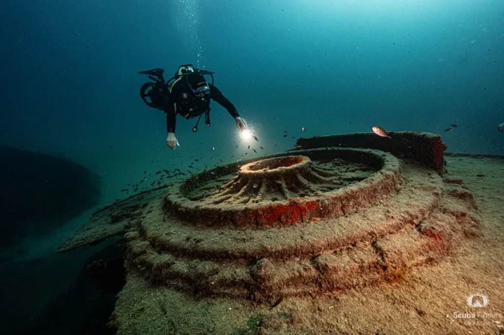 Diver lighting up a sunken structure with a torch during the wreck diving course in Malta